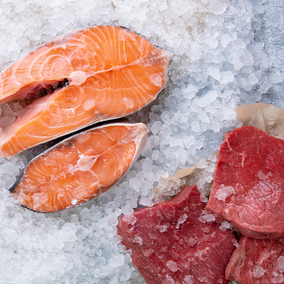 Lachsstück und Fleischstücke auf einer Marmorplatte