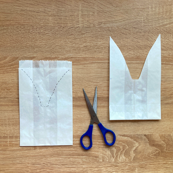 Ausgestanzte Bastelanleitung mit Papierstück und Schere auf einem Holztisch.