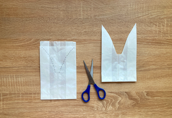 Ausgestanzte Bastelanleitung mit Papierstück und Schere auf einem Holztisch.