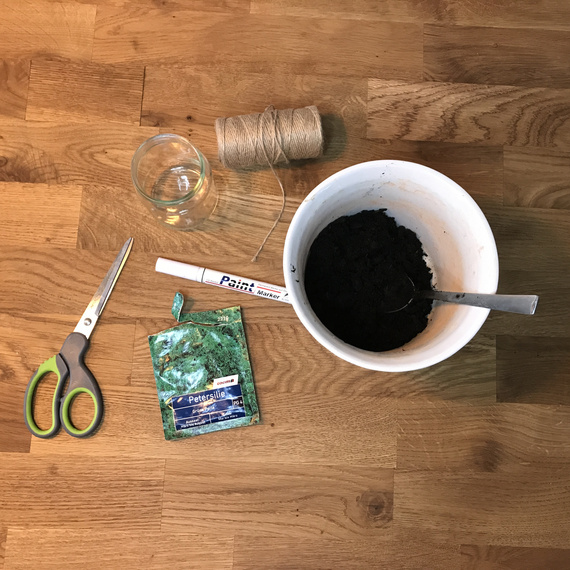 Materialien für den Anbau von Petersilie: Schüssel mit Erde, Wasserglas, Schere, Marker und Schnur auf Holzoberfläche.