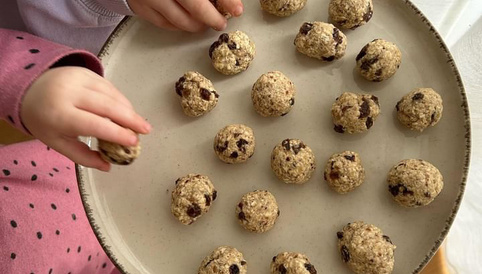 Aufsicht auf Teller mit Energyballs, der von Kinderhänden gehalten wird