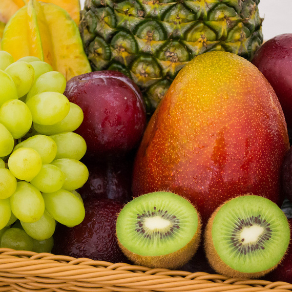 Obst in einer Holzkiste, Kiwi, Weintrauben, Mango und Pflaumen im Vordergrund