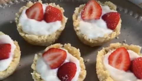 Mini-Keks-Delights mit Grießbrei und frischen Erdbeeren auf einem Teller, dekoriert mit grünen Pflanzen im Hintergrund.
