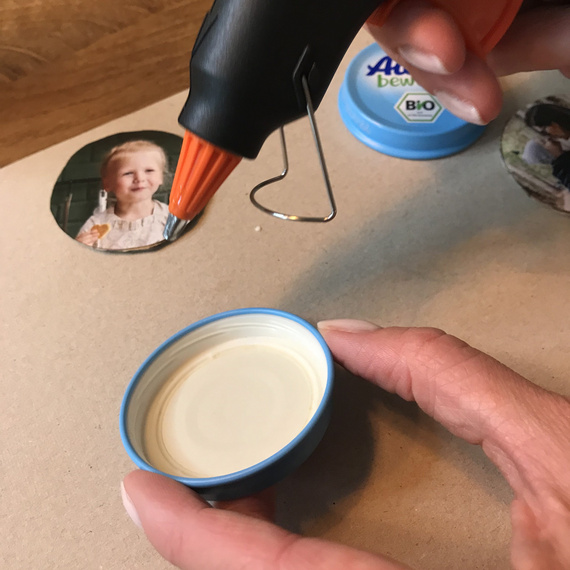 Heißklebepistole, die eine kleine Menge Kleber auf einer blauen Kunststoffschale platziert, um Bastelprojekte anzufertigen.