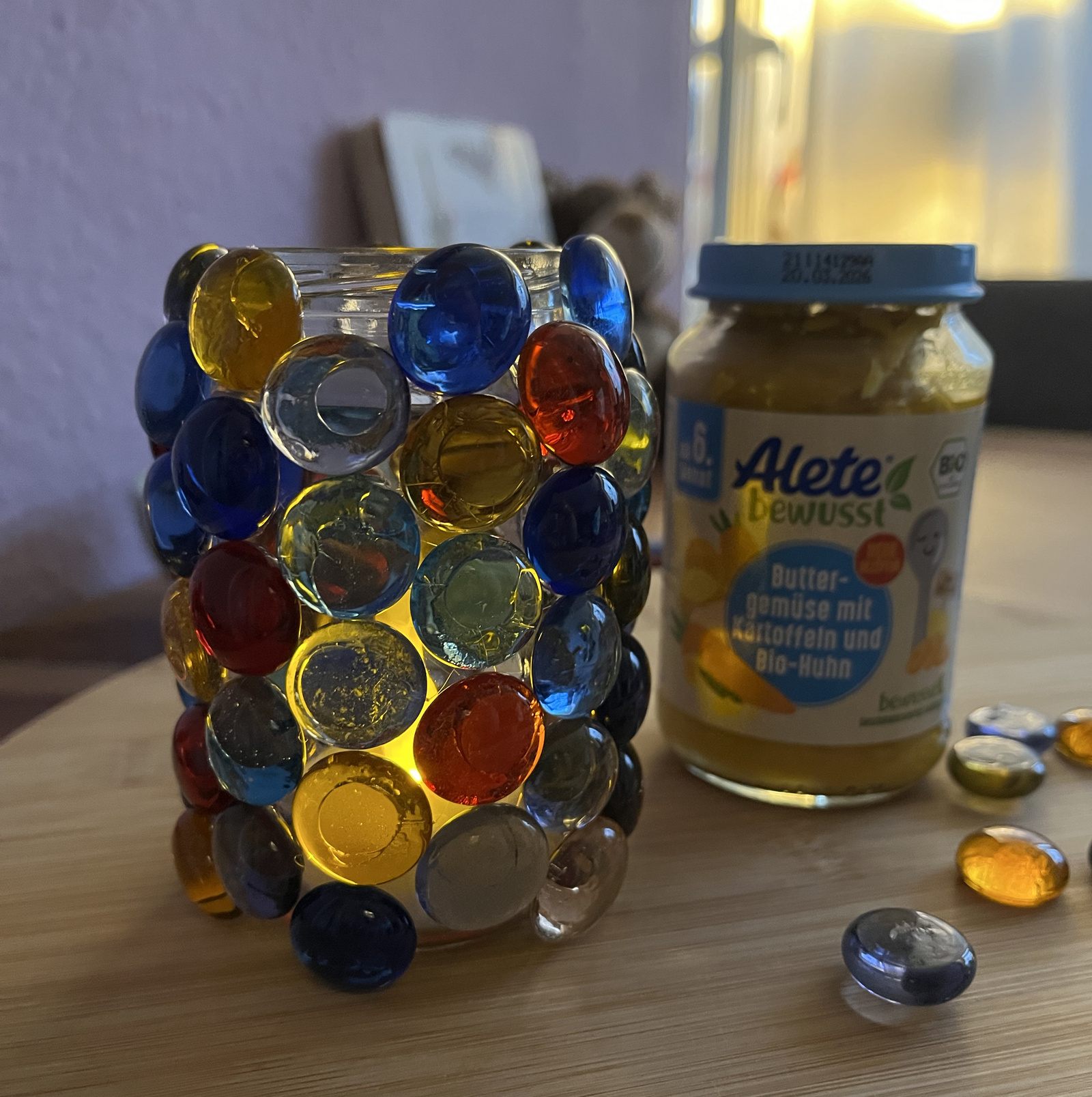 Bunt verziertes Aletegläschen mit leuchtenden Steinen neben einem Glas ALETE Buttergemüse.