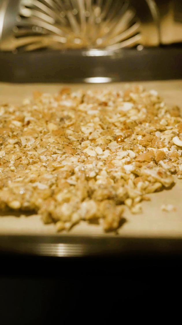 Karamellisierte Nussmischung mit Haferflocken auf einem Backblech, bereit zum Abkühlen.