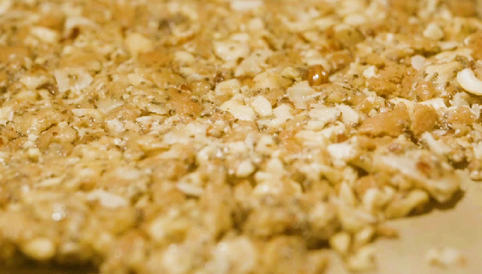 Karamellisierte Nussmischung mit Haferflocken auf einem Backblech, bereit zum Abkühlen.